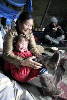 picture of old lady helping child wear Mongolian Boots
